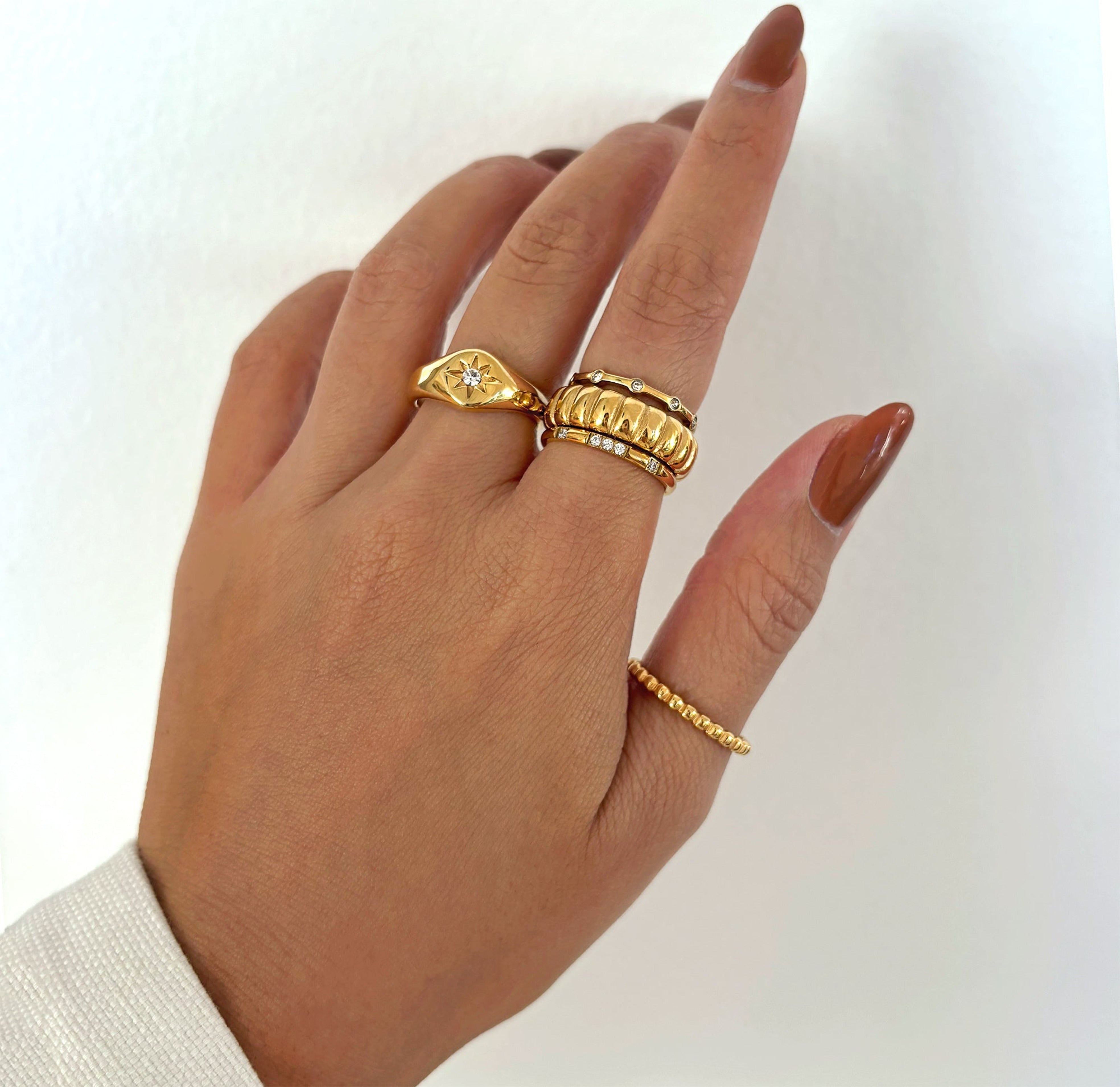 gold ribbed ring stacked with dainty pave ring and august starburst signet ring. Waterproof jewelry