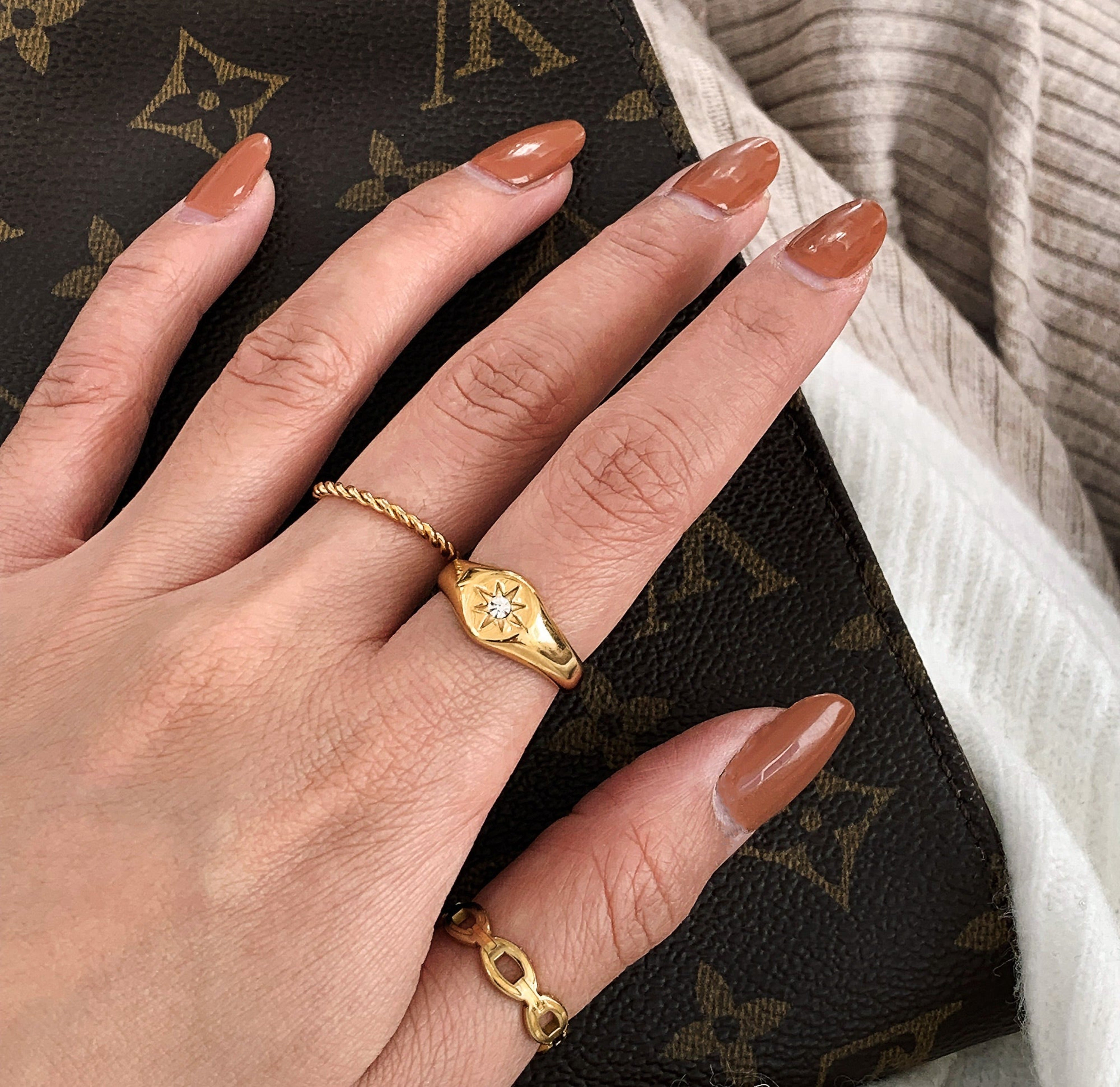gold starburst signet ring worn on hand model stacked with the  gold dainty Sophie twist ring  and the Dylan gold chain ring worn on the thumb